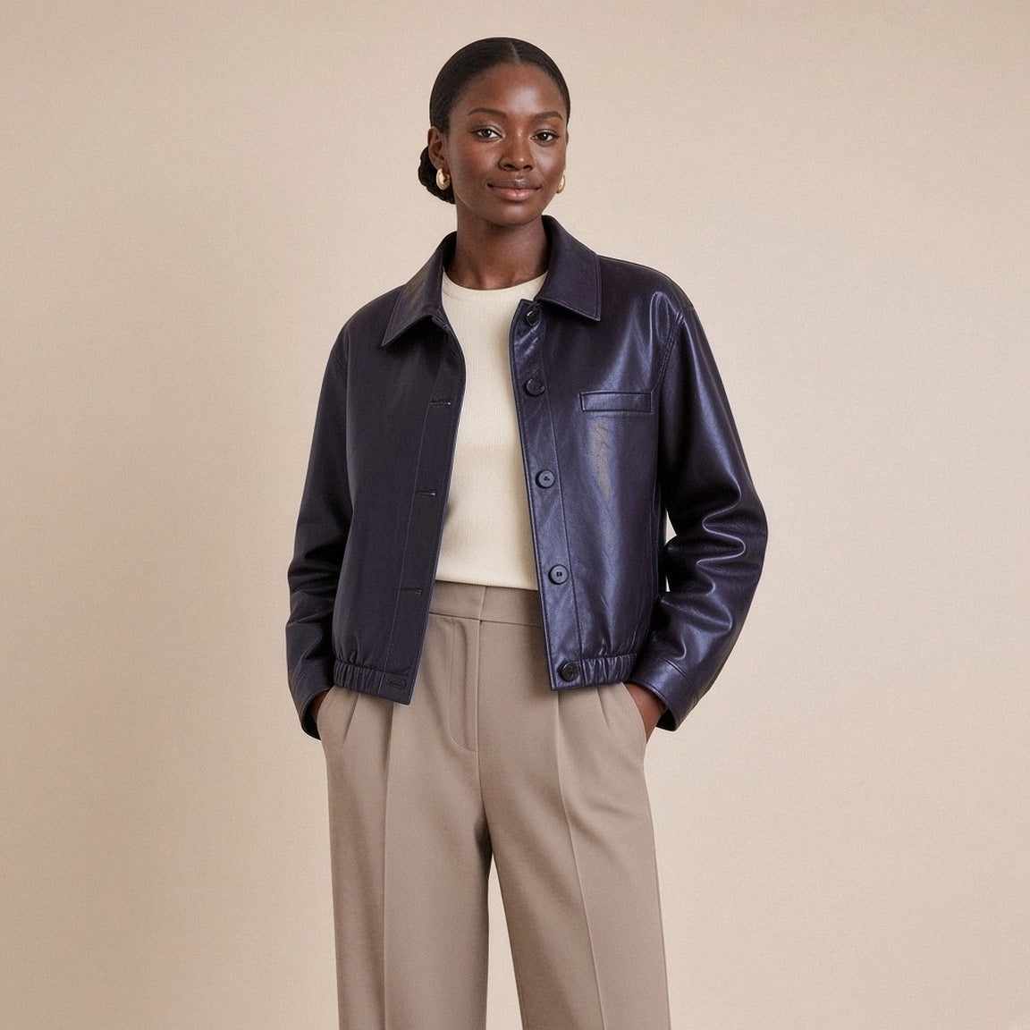 Veste ample en cuir de mouton noir aubergine à col chemise portée ouverte, mains dans les poches du pantalon