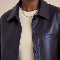 Détail du col chemise, des boutons et de la poche poitrine de la veste en cuir noir aubergine