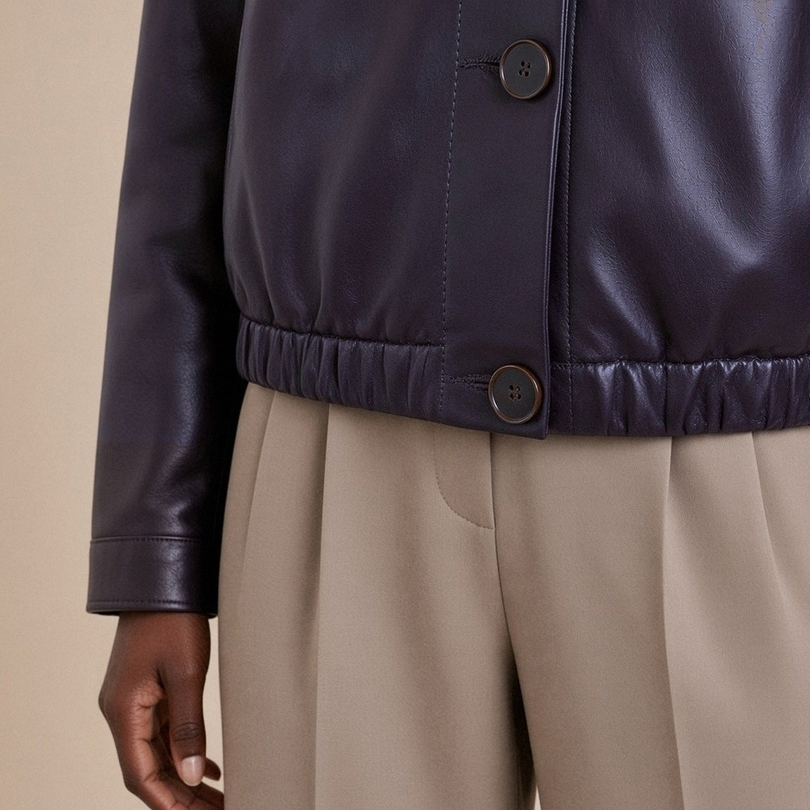 Détail du bas froncé élastiqué et des boutons de la veste en cuir noir aubergine