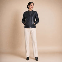 Veste courte en cuir de mouton à col montant noire portée, mains dans les poches
