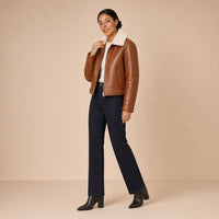 Veste courte ouatinée en cuir de mouton à col peluche SAKIWE caramel brûlé, de trois quarts, main sur le col